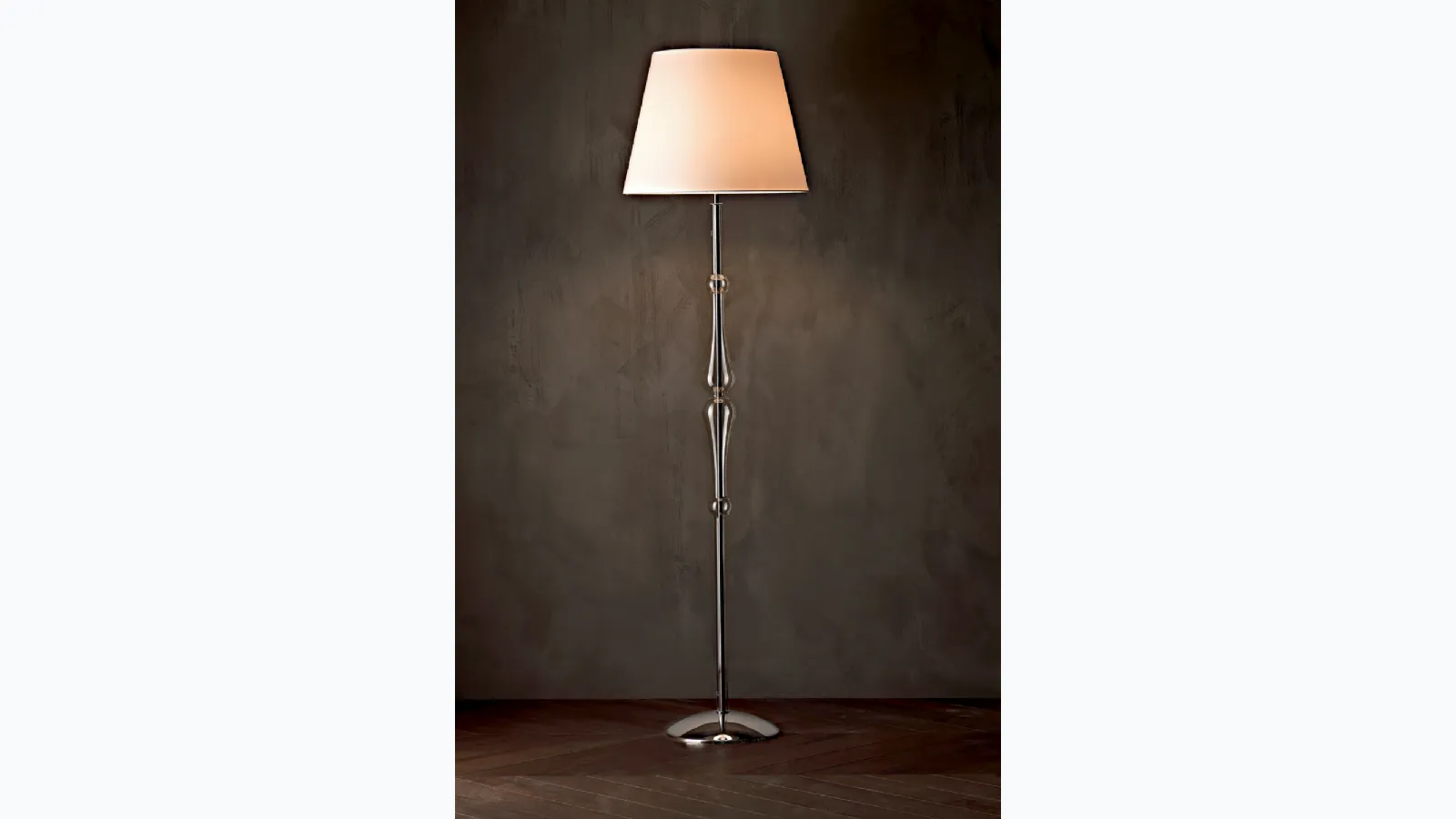 Lampada da terra Miss con struttura cromata,  stelo sagomato in pirex trasparente e paralume in tessuto di Le Fablier
